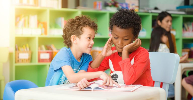 Row of multiethnic elementary students reading book in classroom. Vintage effect style pictures.